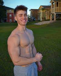 a shirtless man standing in the grass in front of a house